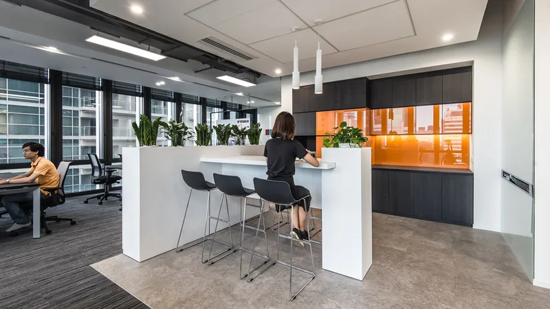 Văn phòng mở hiện đại ở Thành phố Hồ Chí Minh với quầy bar đứng, ghế đen và tủ kính cam nổi bật.