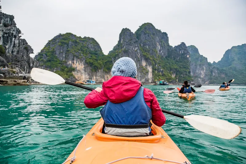 Một người chèo kayak lướt qua làn nước xanh ngọc giữa những đảo đá vôi hùng vĩ ở vịnh Hạ Long.
