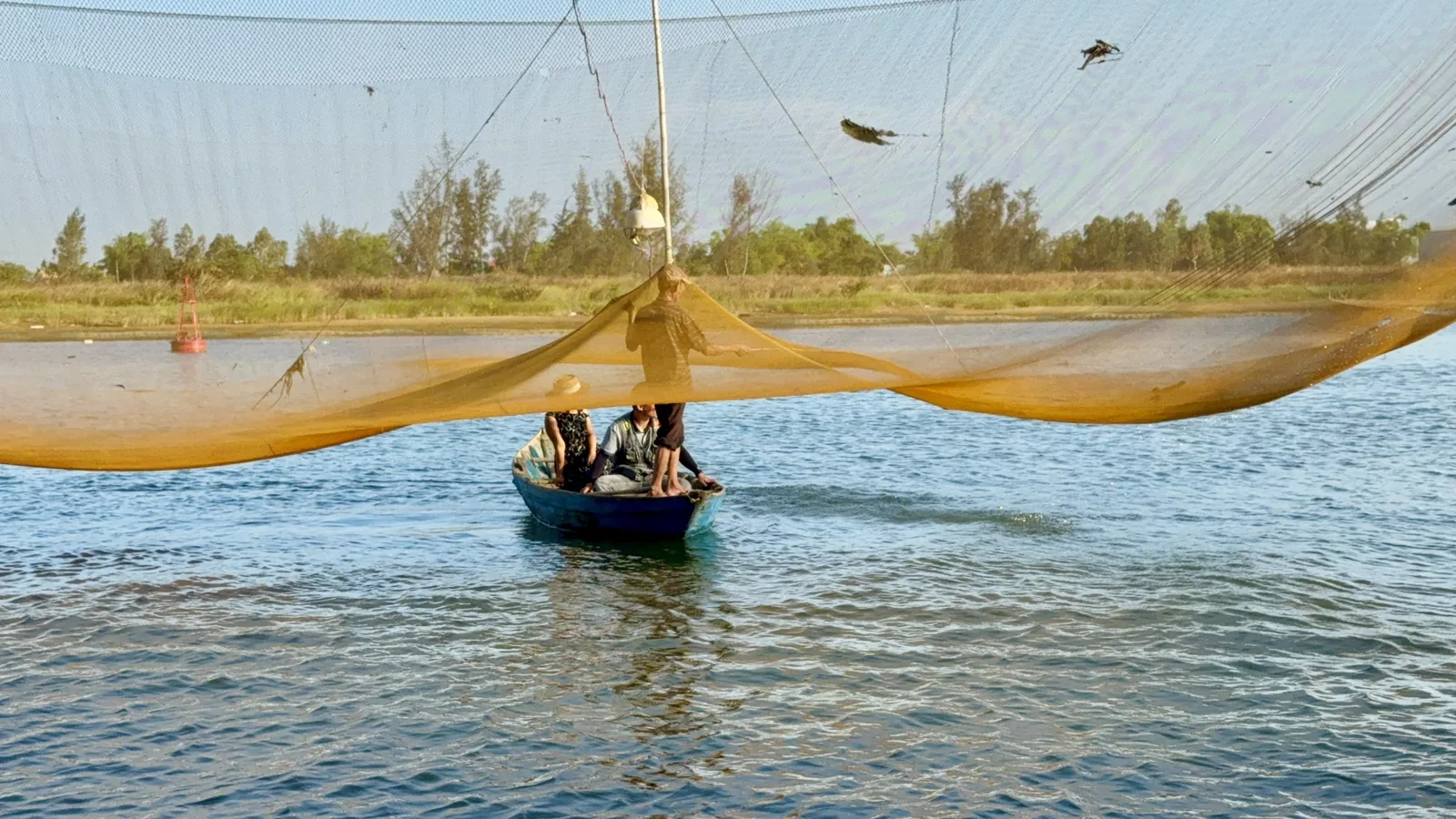 Những người đánh cá vận hành lưới vó khổng lồ trên chiếc thuyền nhỏ giữa đầm nước gần Hội An.